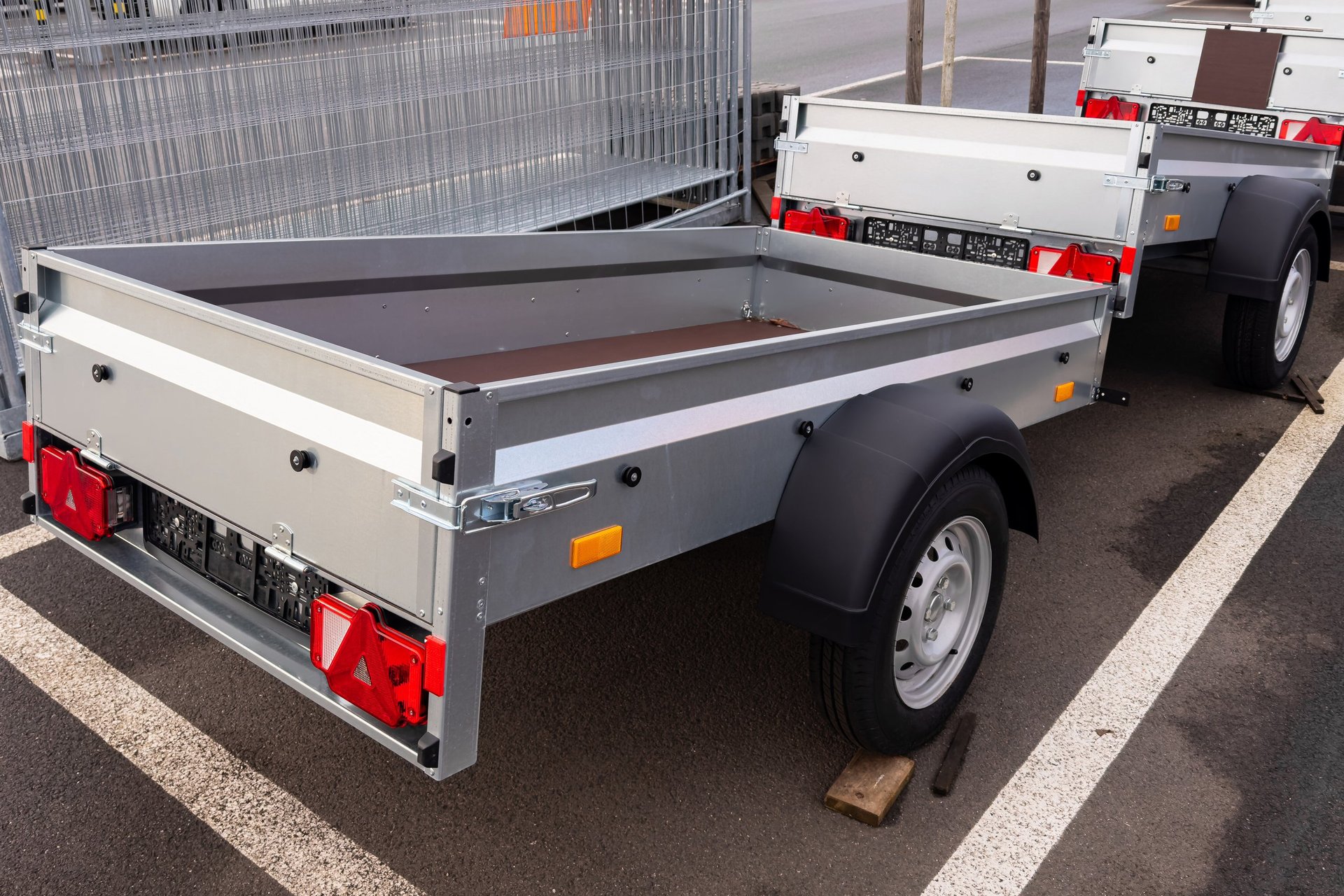 Cargo trailers for passenger car are lined up in a large parking area, ready for various hauling tasks