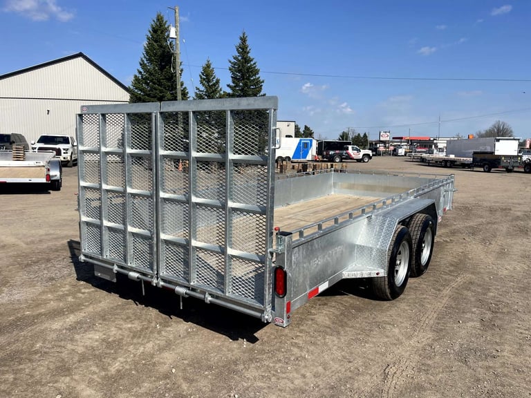 Silver utility trailer with metal mesh sides and open deck bed in an industrial lot